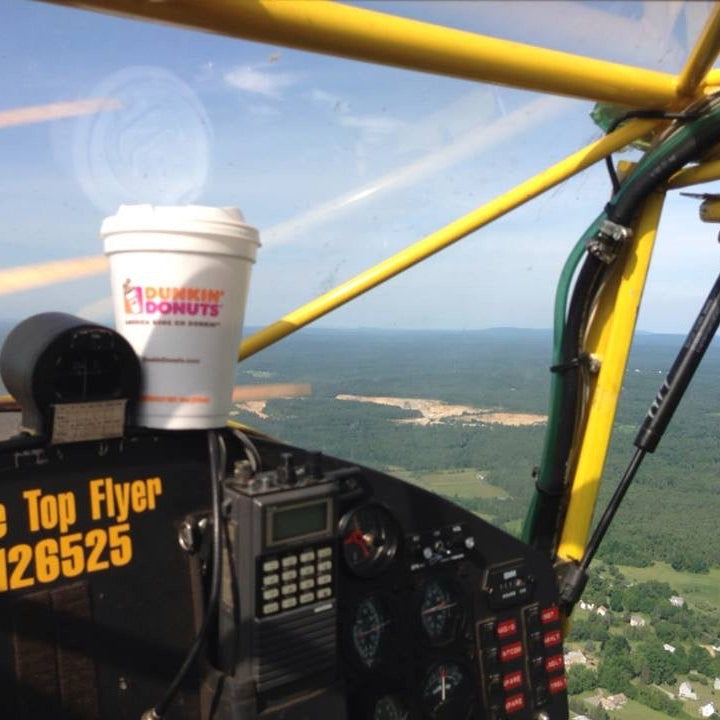 Cup with a logo on a helicopter dashboard overlooking a scenic landscape